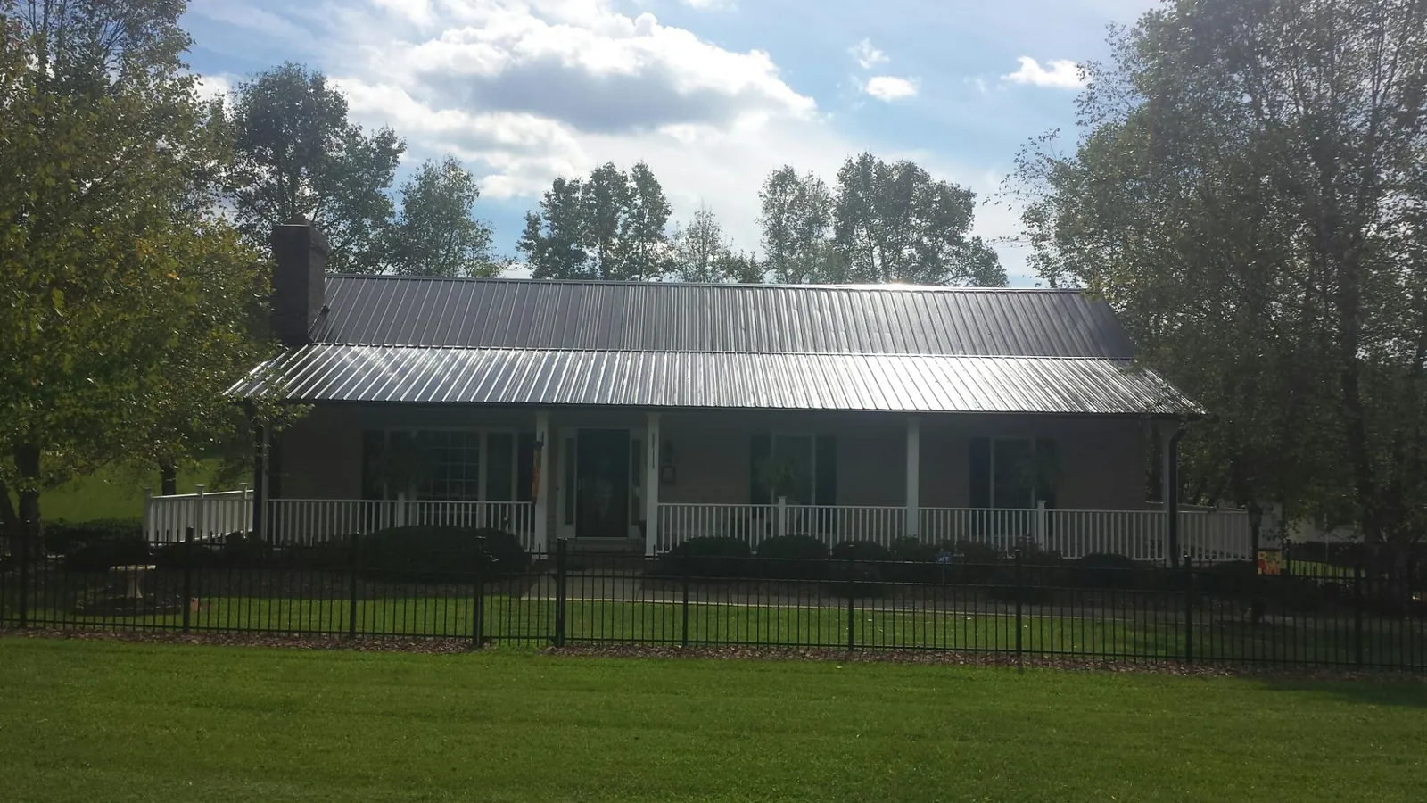 Gray metal roof on a brick ranch with a full width front porch — Gutter Guard Installation work by our crew in Kouts