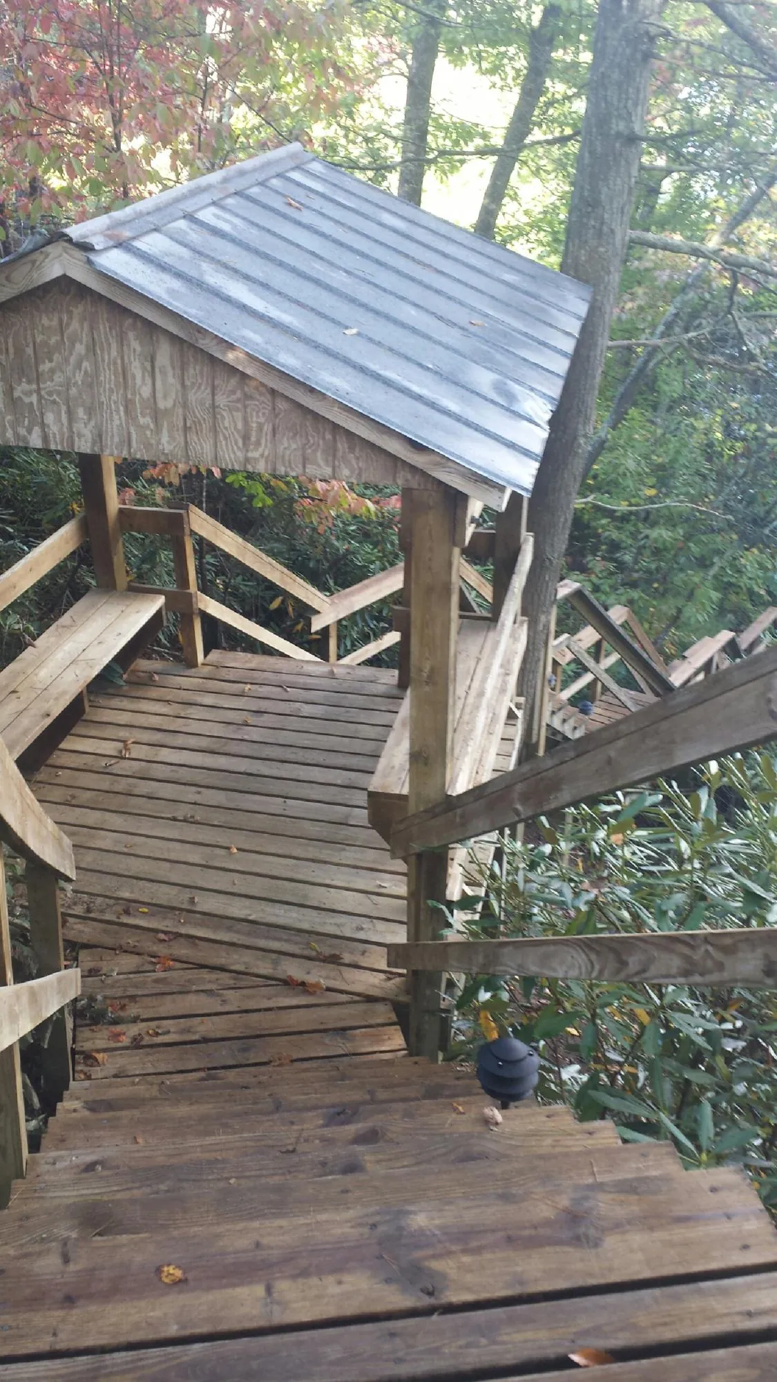 Metal roofed shelter over wooden steps on a wooded walkway — Skylight Repair & Installation work by our crew in Kouts