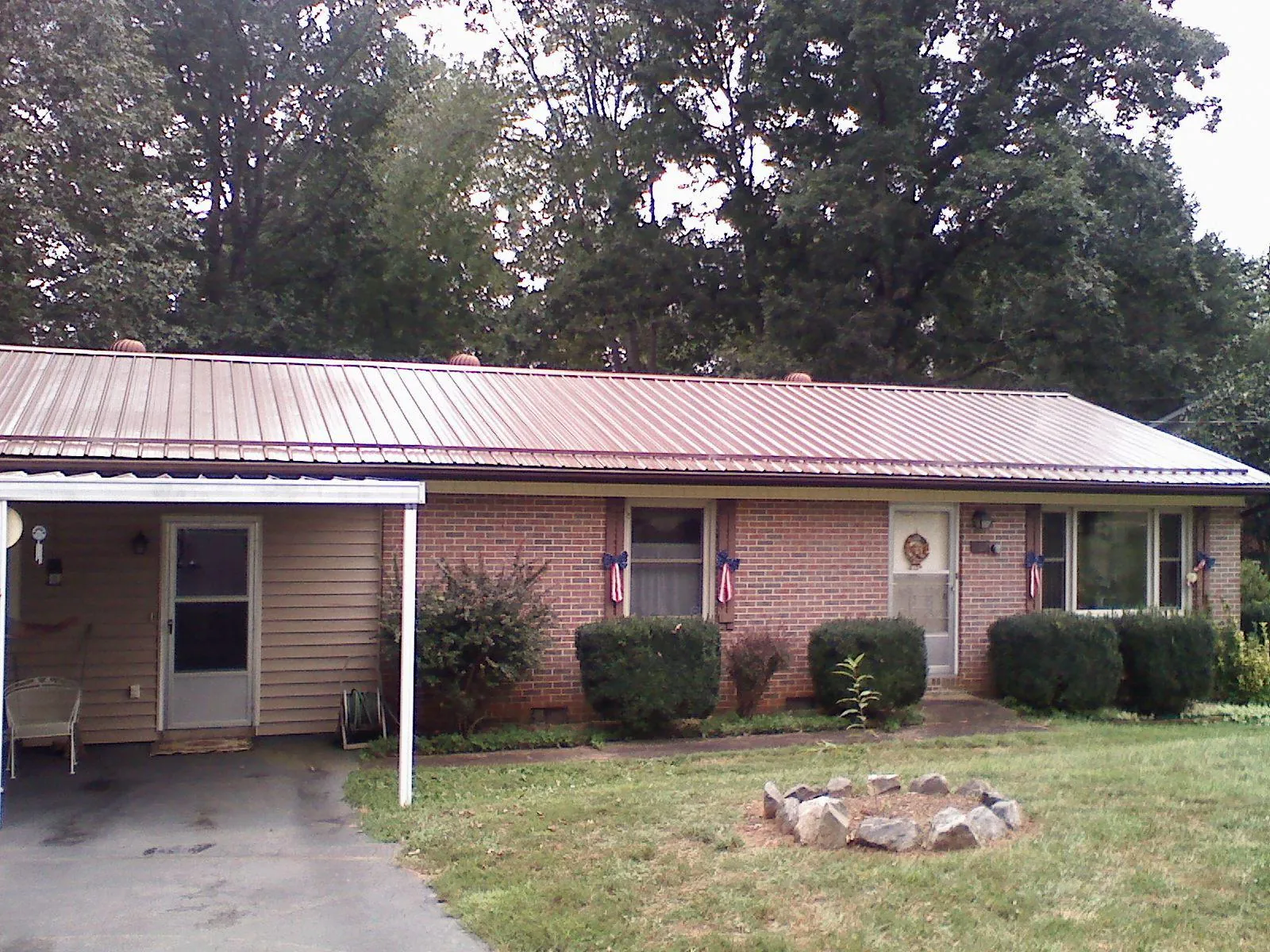 Bronze metal roof and carport on a brick ranch home — Roof Repair work by our crew in Kouts