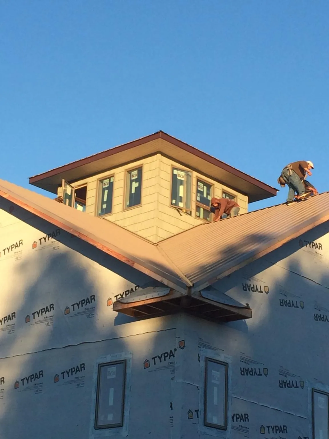 Roofers working around a rooftop cupola on a new metal roof at sunset — Roof Waterproofing in Kouts by Roofing Brothers